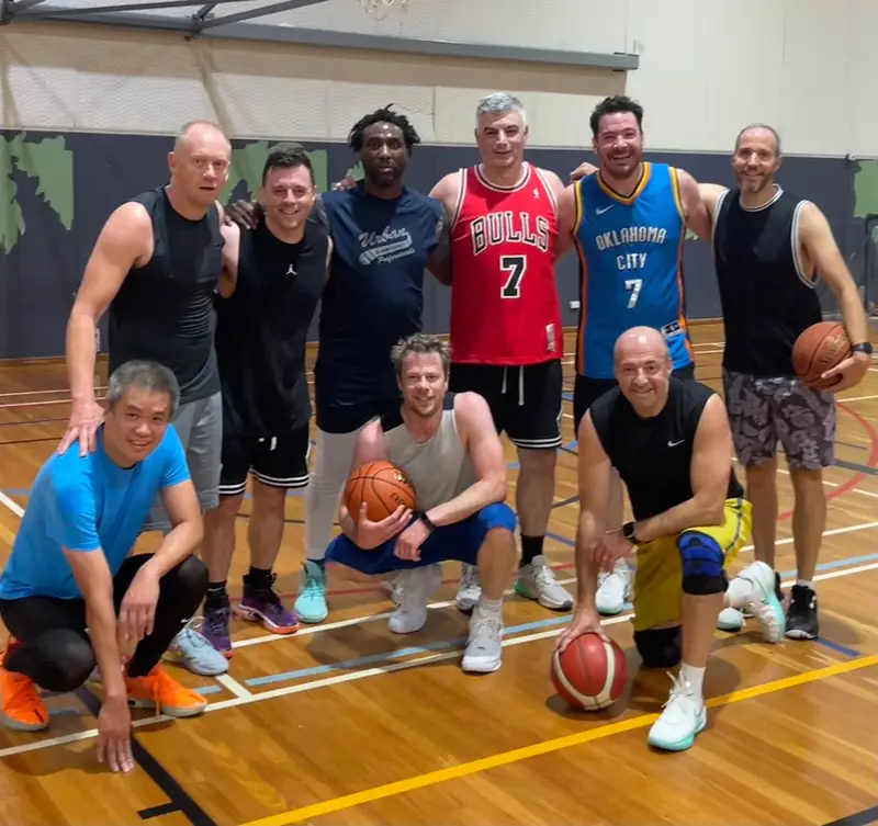 The regular Friday Hoops crew laughing together on court after a game